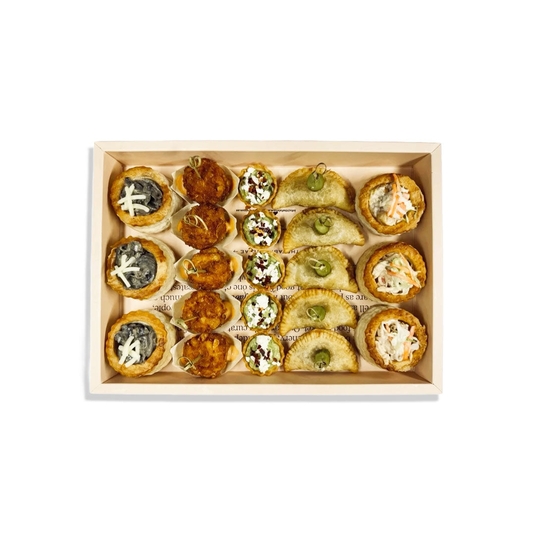 Box of assorted mini quiches with different fillings on a white background