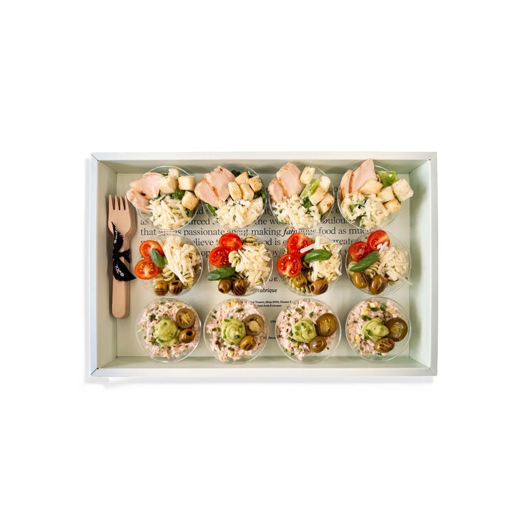 Tray of assorted small salads with a fork and knife on a white background