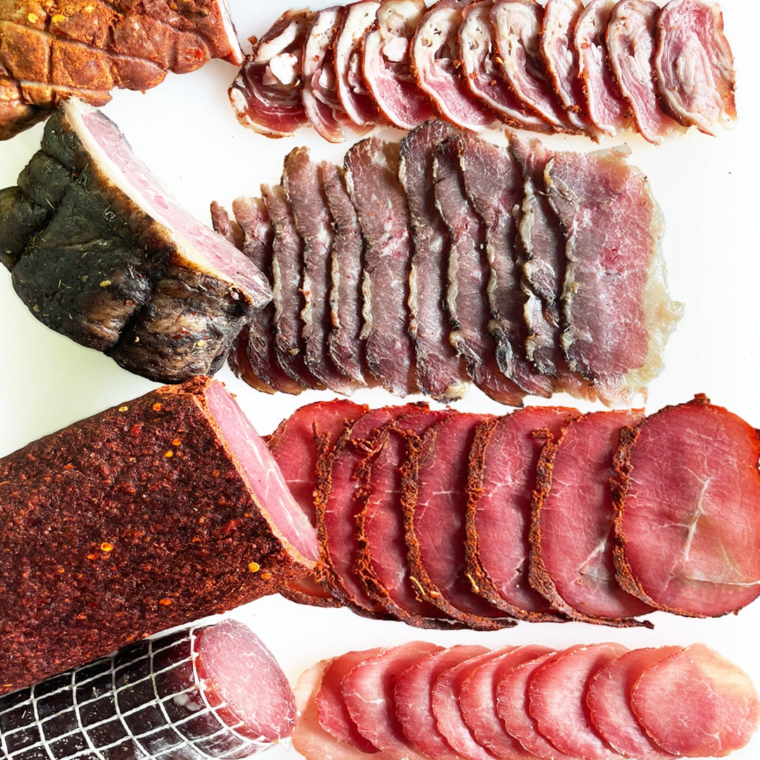 Assorted sliced cured meats on a white background