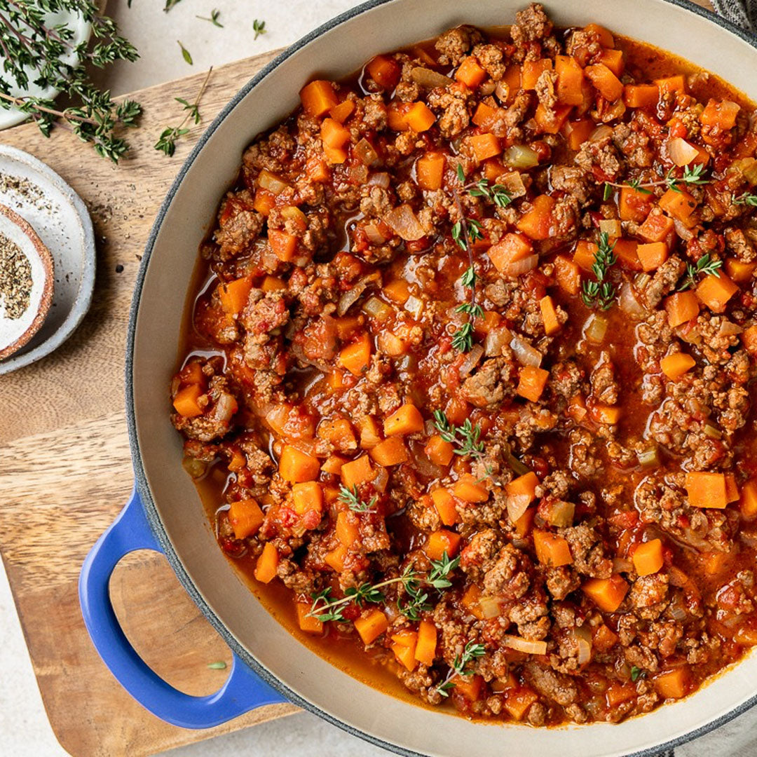 Stew with ground meat and vegetables in a pan on a wooden board