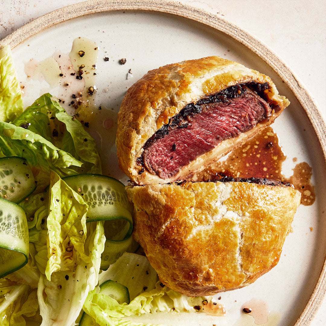 Baked meat dish with a golden crust on a plate with salad