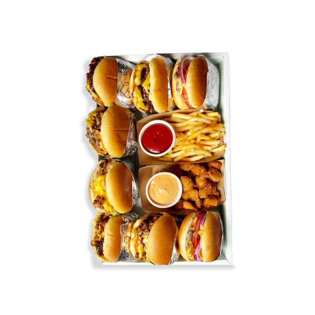 Assorted burgers and fries in a tray with condiments on a white background