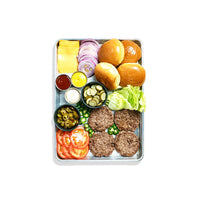 Burger ingredients including buns, lettuce, tomatoes, and condiments on a metal tray.