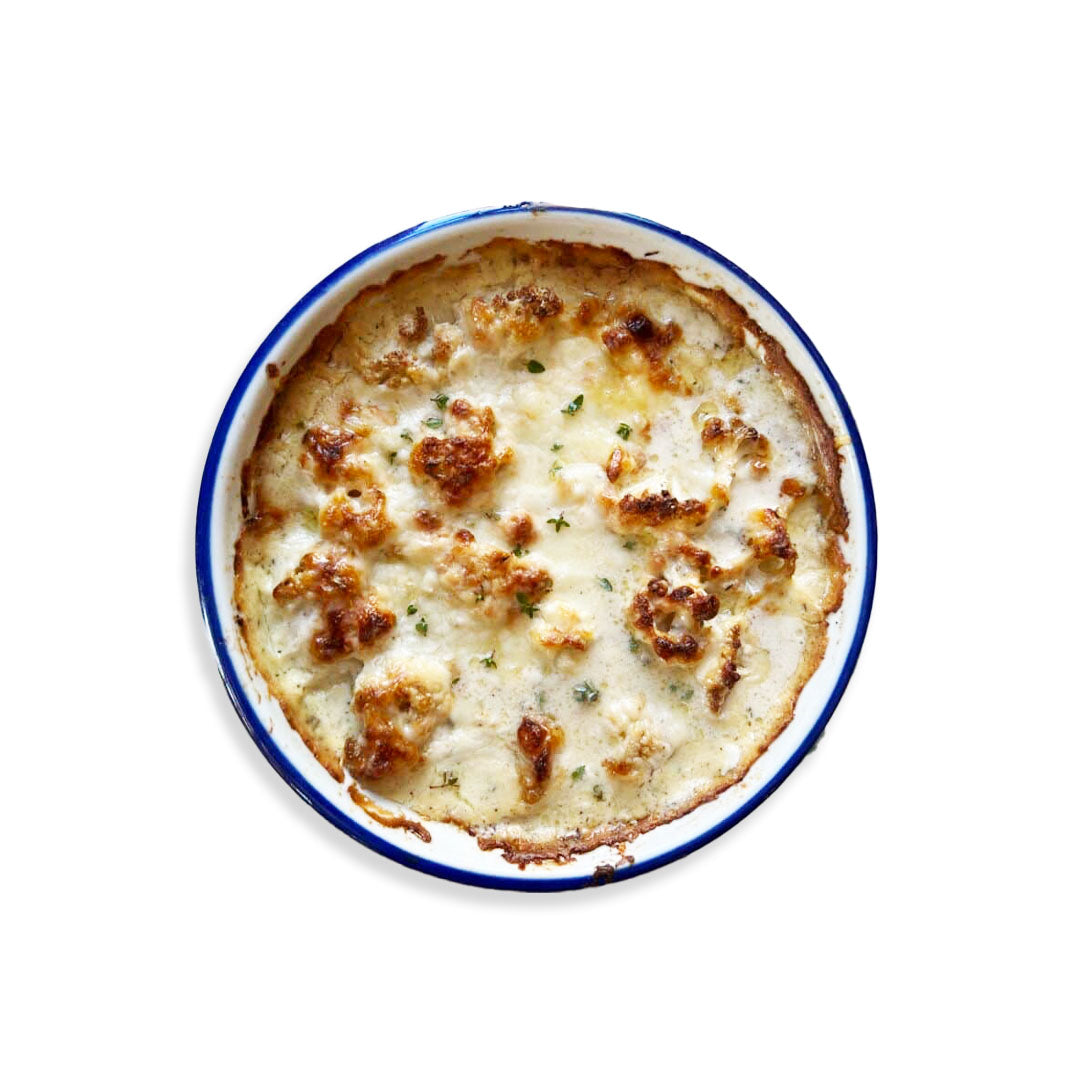 Baked dish with a creamy topping in a white bowl with blue rim on a white background