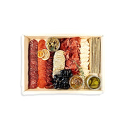 Assorted meats, cheeses, and fruits in a wooden box on a white background