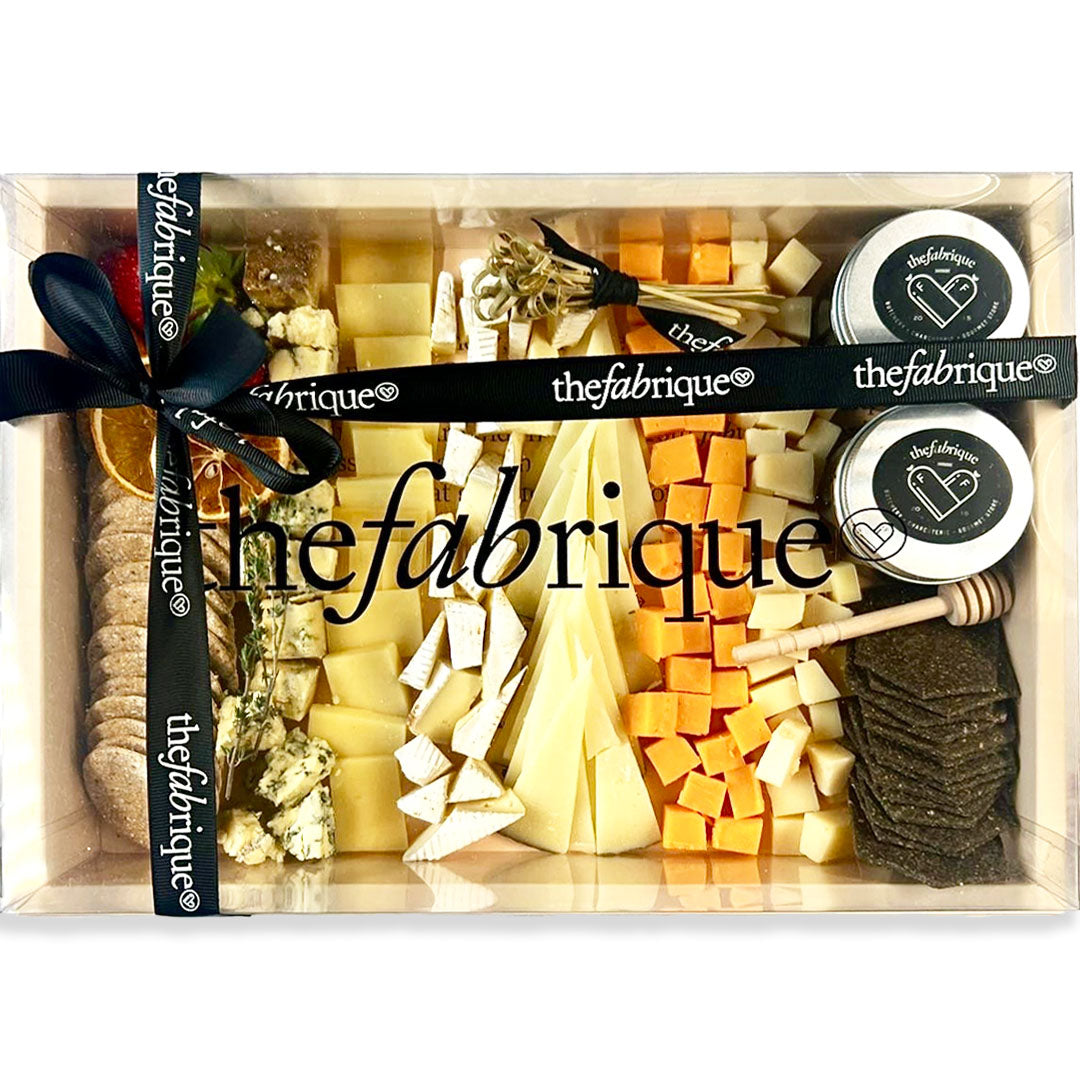 Assorted cheeses, crackers, and fruits in a wooden box on a white background in a Box 