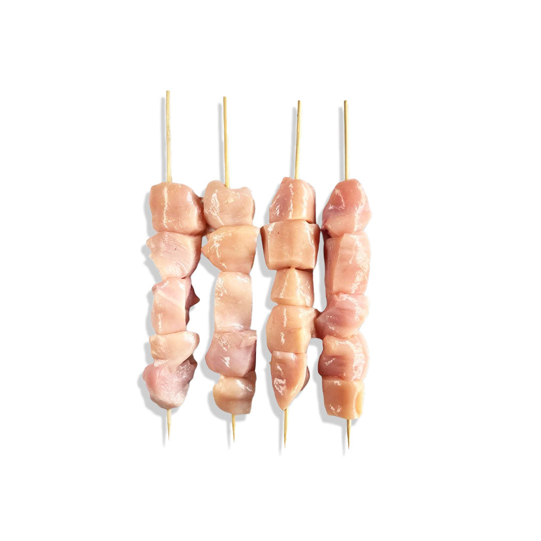 Three skewers of raw chicken on a white background
