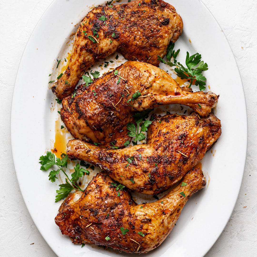 Roasted chicken drumsticks on a white plate with parsley garnish