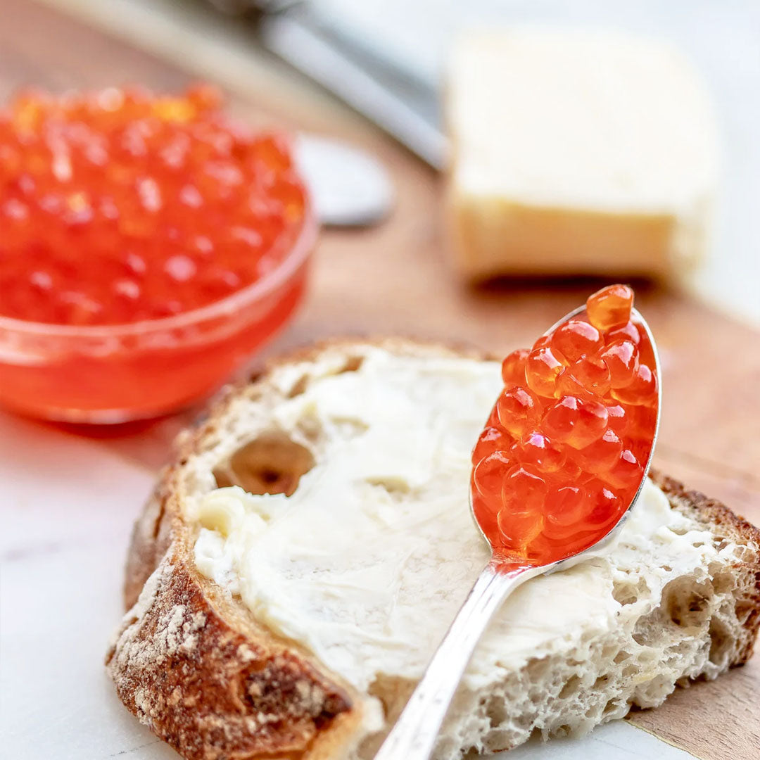 Bread with cream cheese and red caviar on a wooden surface