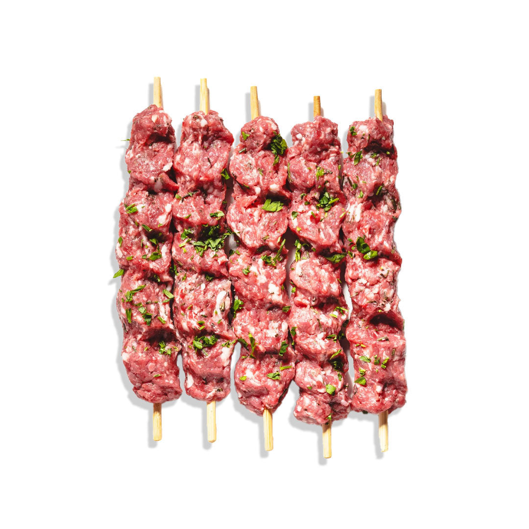 Raw meat skewers with visible herbs on a white background
