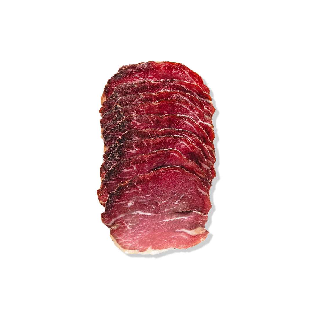 Thinly sliced artisanal lamb prosciutto on a gourmet grazing board with cheeses and fresh fruits