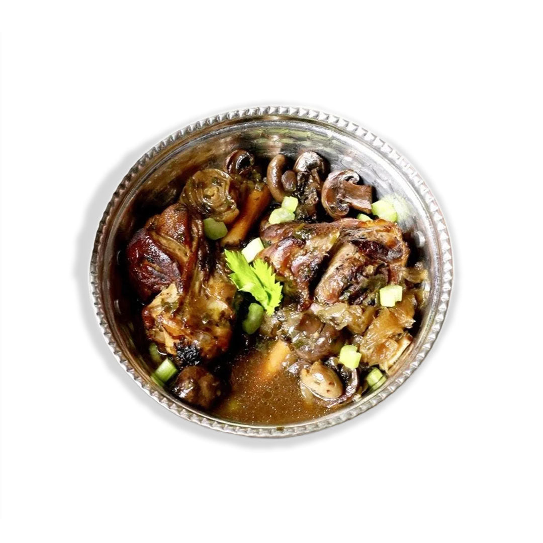 Stewed meat dish with vegetables in a metal bowl on a white background
