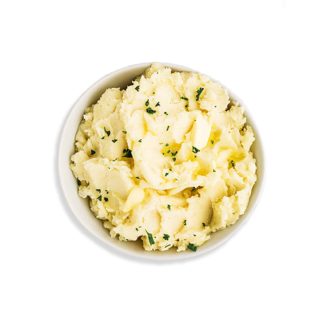 Mashed potatoes with herbs in a white bowl on a white background