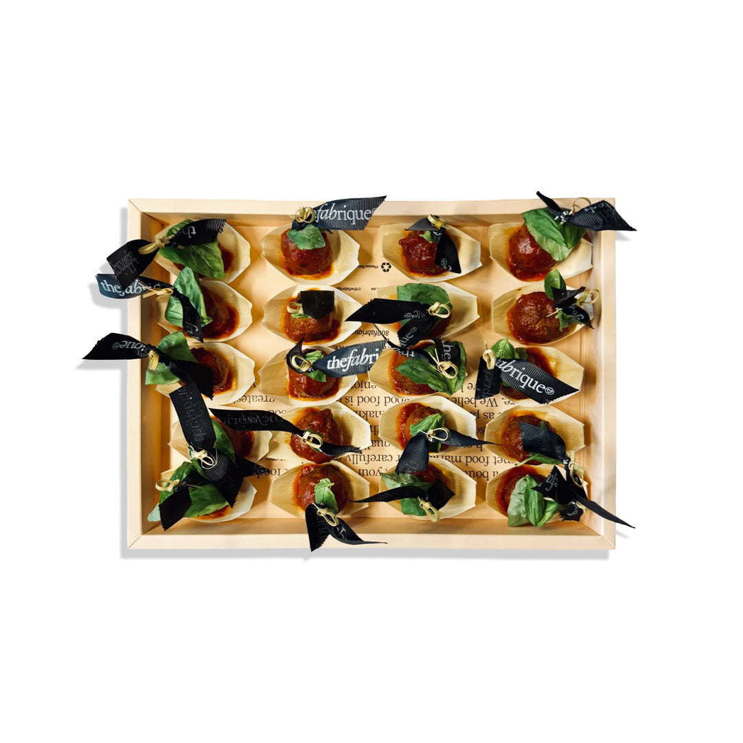 Wooden box with small appetizers and basil leaves on a white background