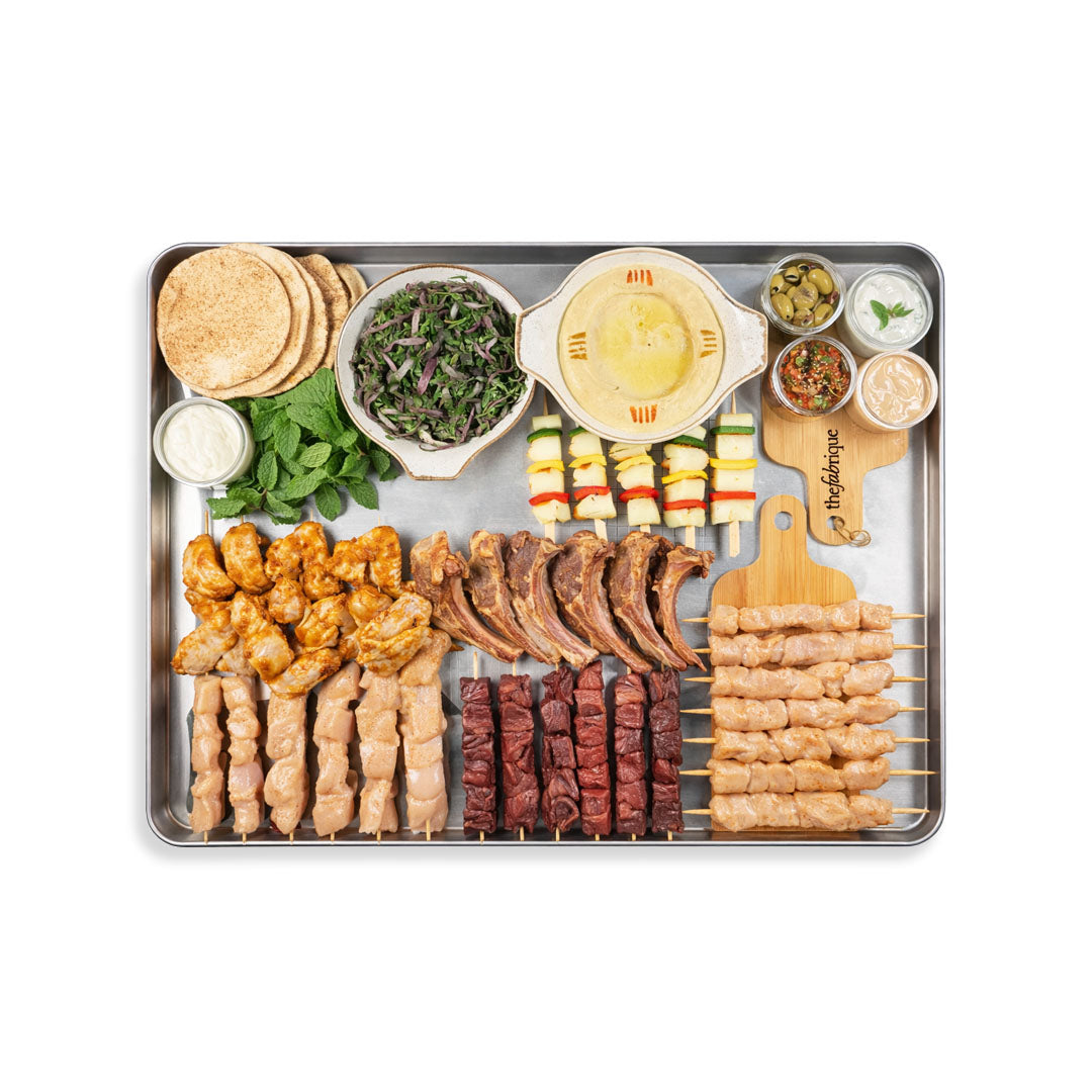 Assorted skewers and appetizers on a platter with a white background