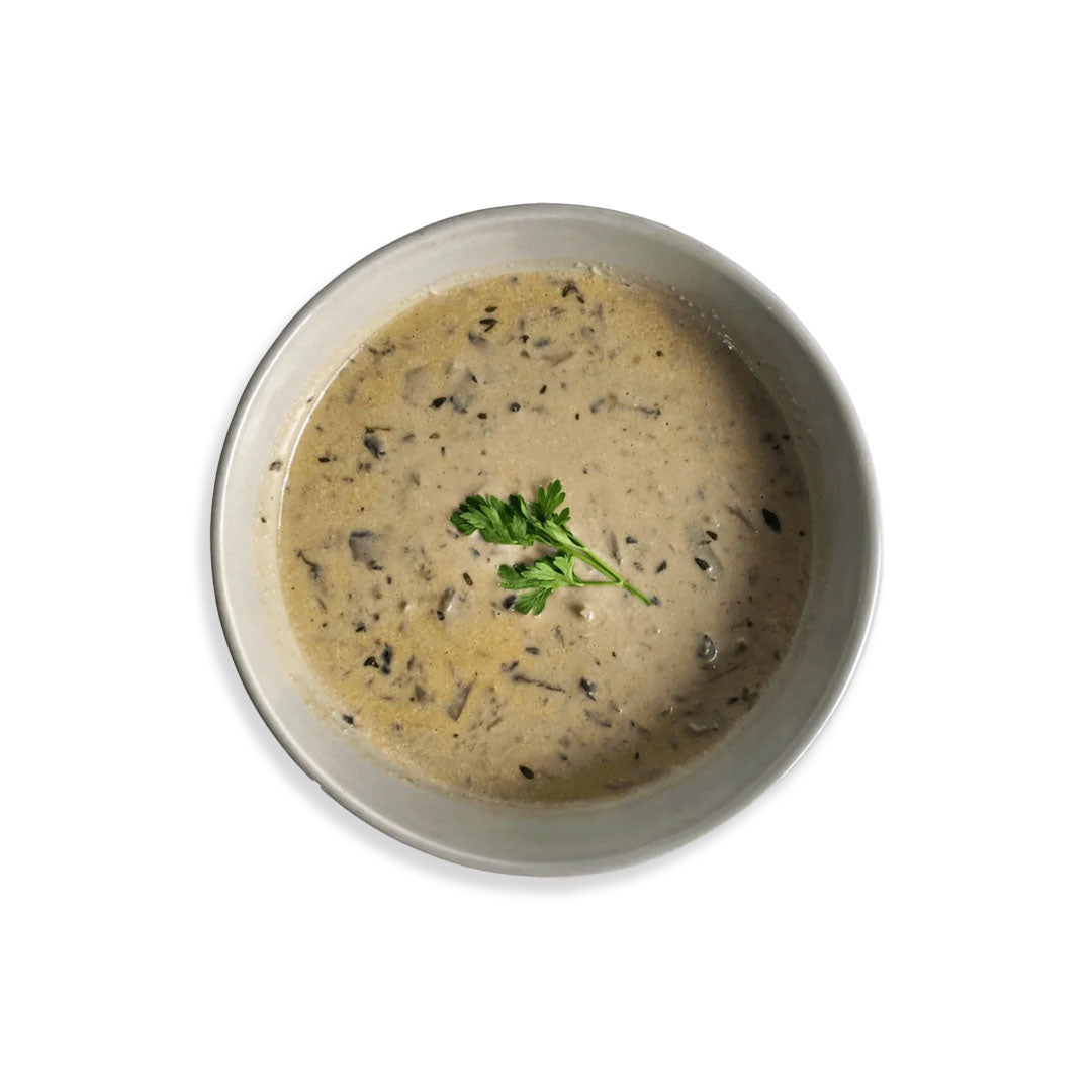 Creamy soup with herbs in a bowl on a white background