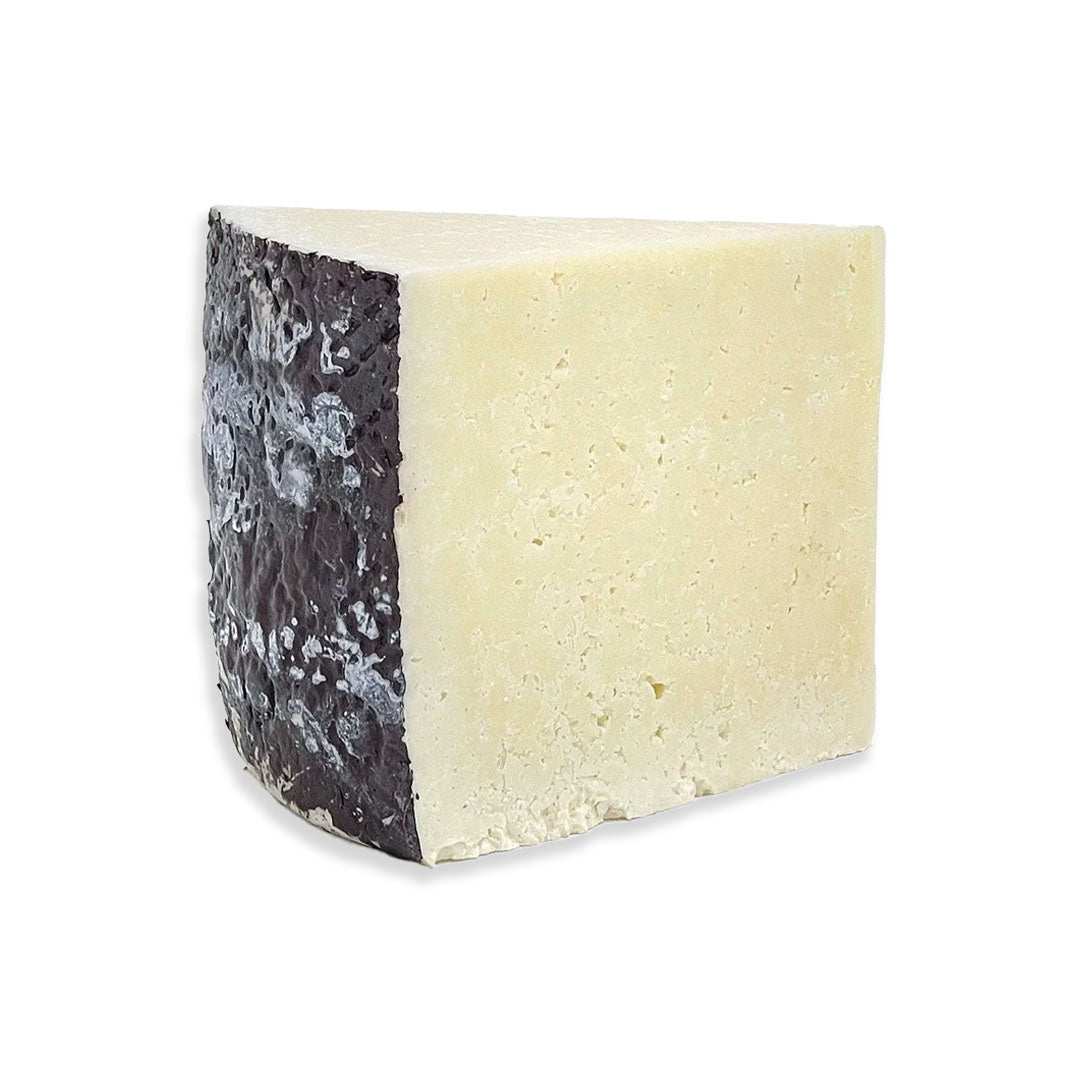 Block of Pecorino Romano cheese with firm texture and salty flavor for grating or serving with olives and cured meats