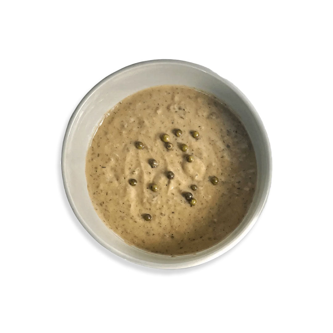 Bowl of creamy soup with visible herbs on a white background