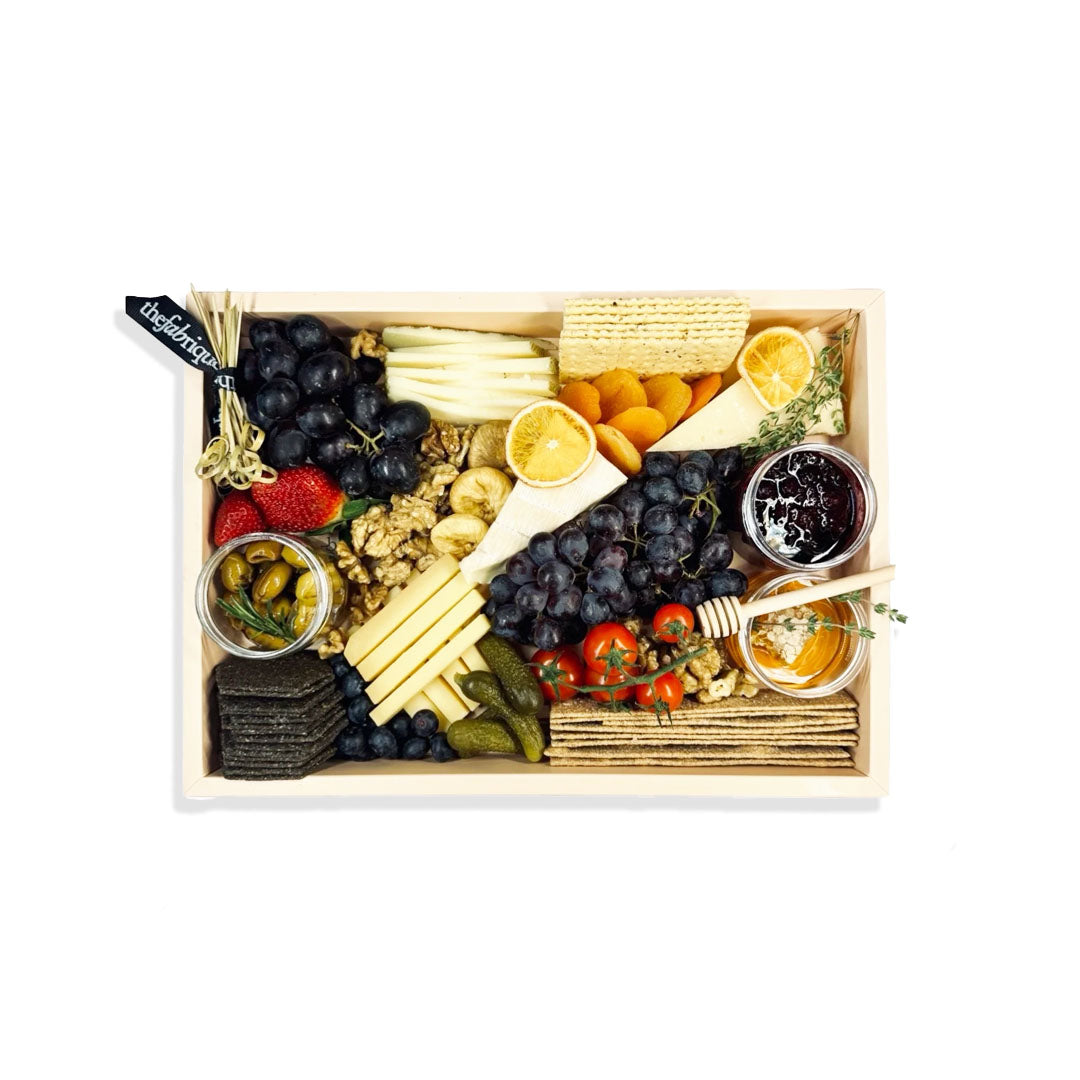 Gourmet food platter with various snacks and fruits in a wooden box.
