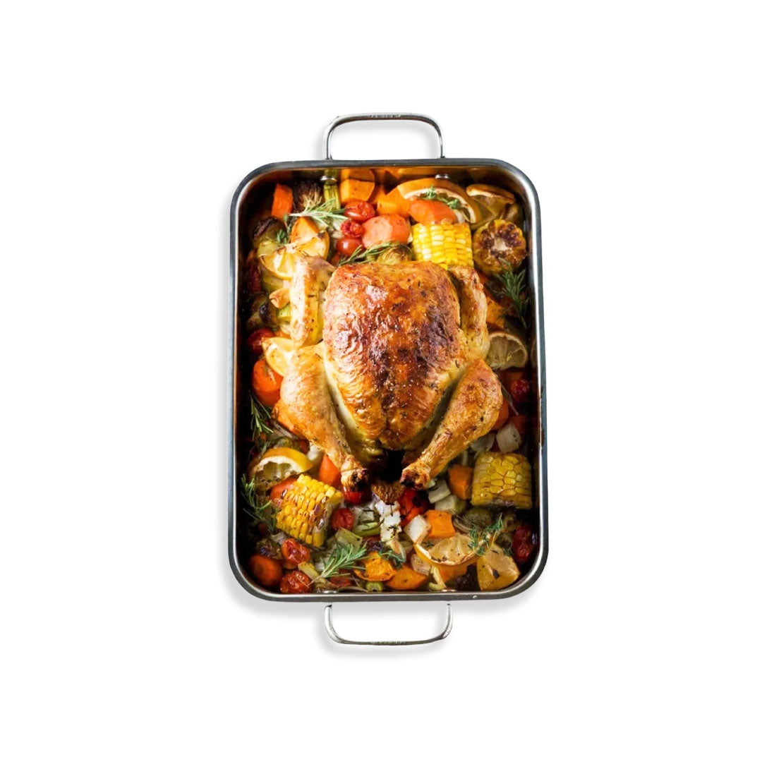 Roasted chicken with vegetables in a rectangular baking dish on a white background