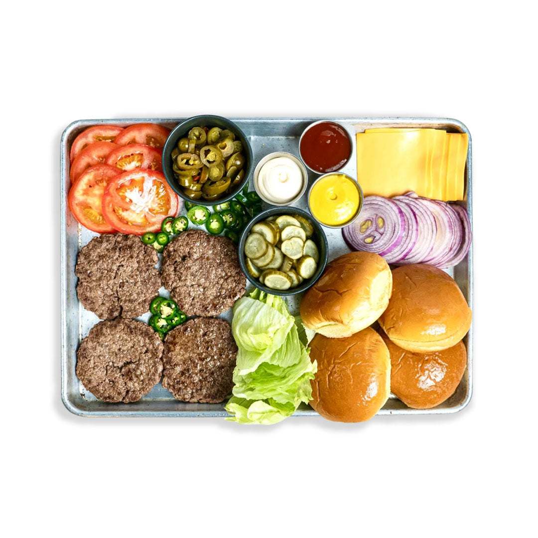 Burger box with fresh patties, buns, cheese, sauces, and vegetables for homemade burgers