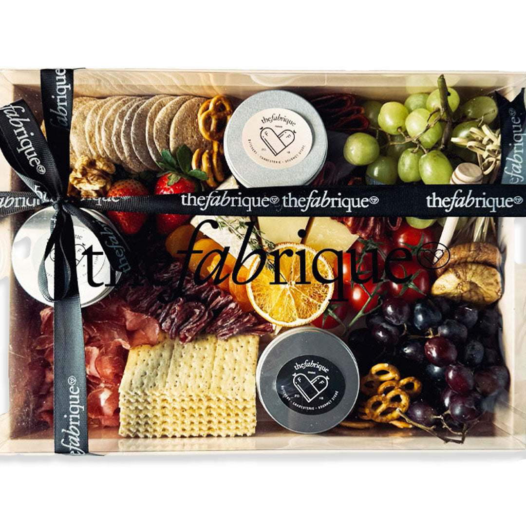 Gourmet food box with meats, cheeses, fruits, and pretzels, branded 'thefabrique'.