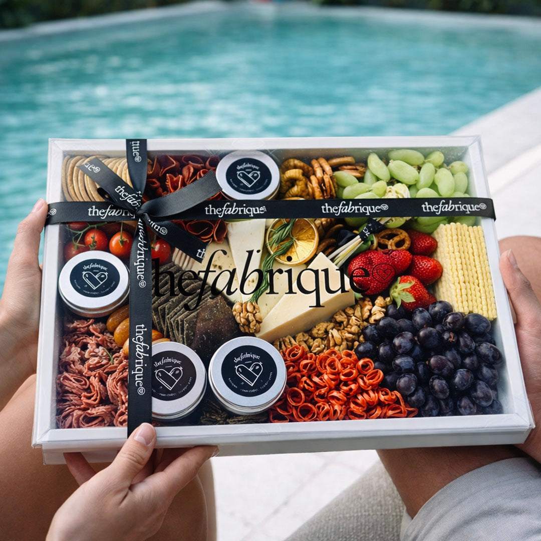 Gift box with snacks and fruits held by hands with a pool in the background