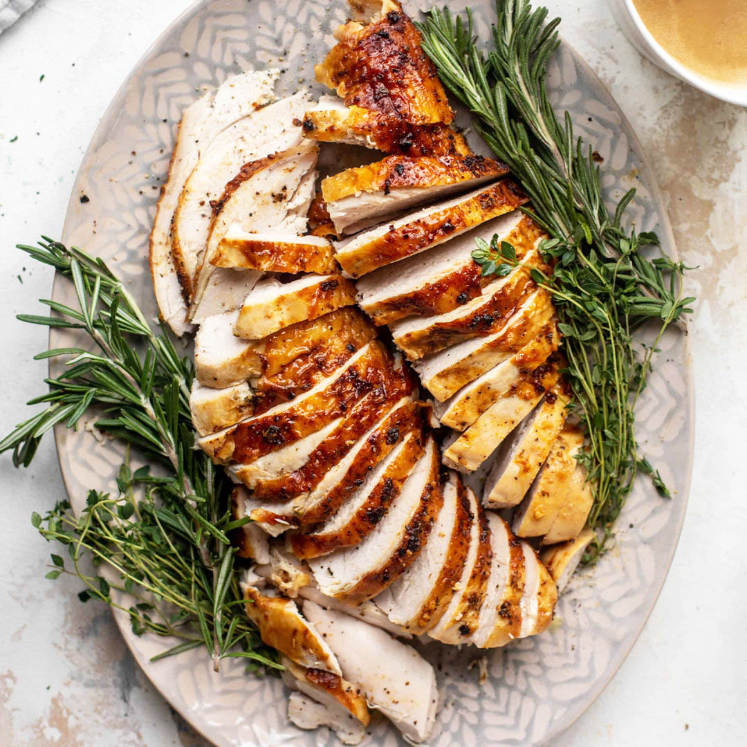Sliced roasted chicken on a decorative plate with herbs