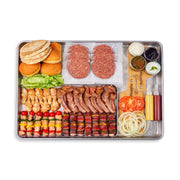 Assorted food items including buns, meats, vegetables, and condiments on a tray with a knife.