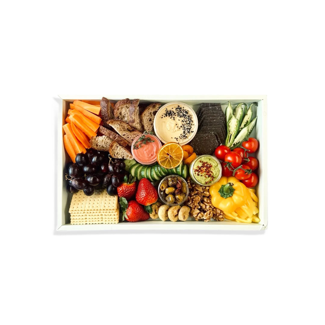 Assorted snacks including fruits, vegetables, and crackers on a white tray.