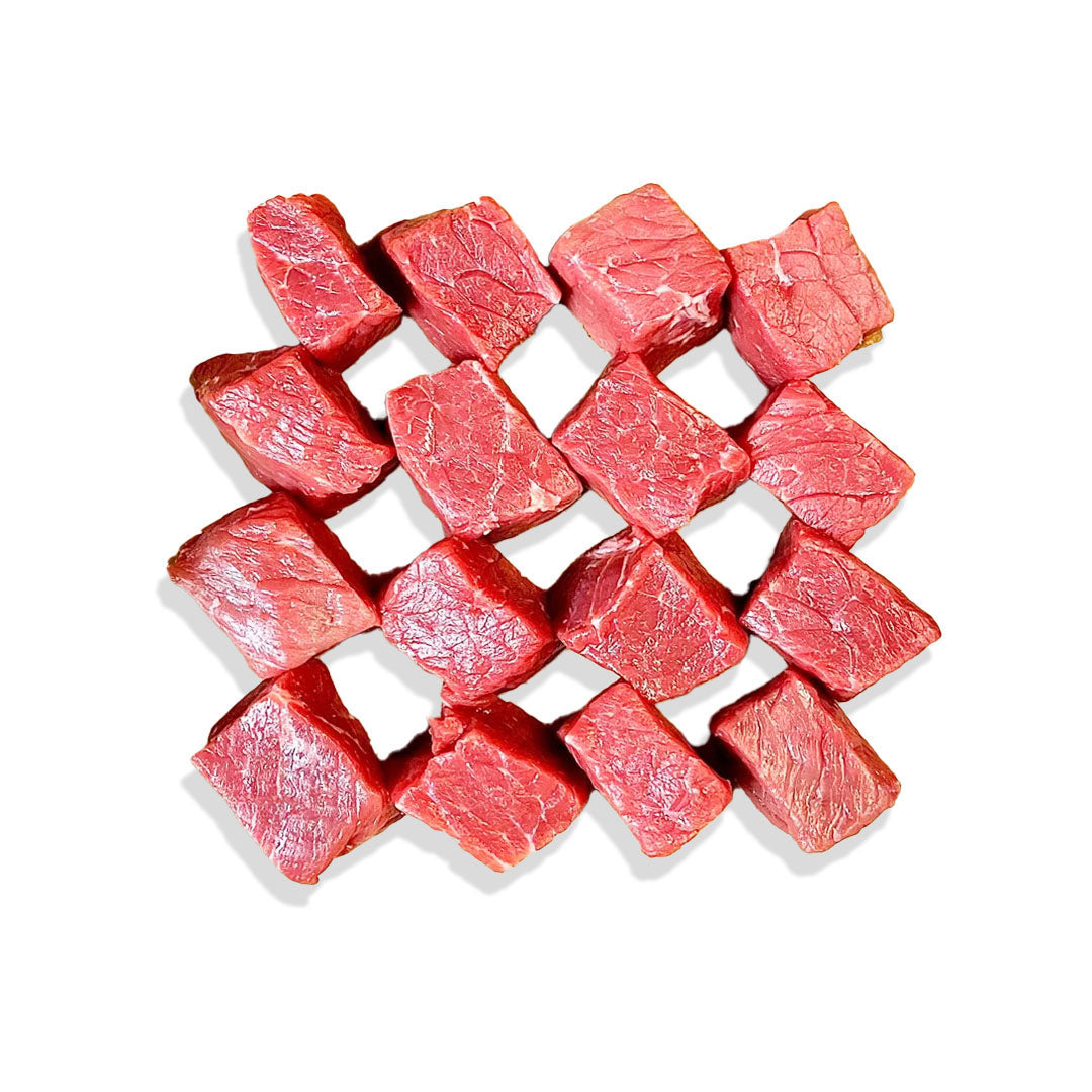 Raw beef cubes arranged in a woven pattern on a white background