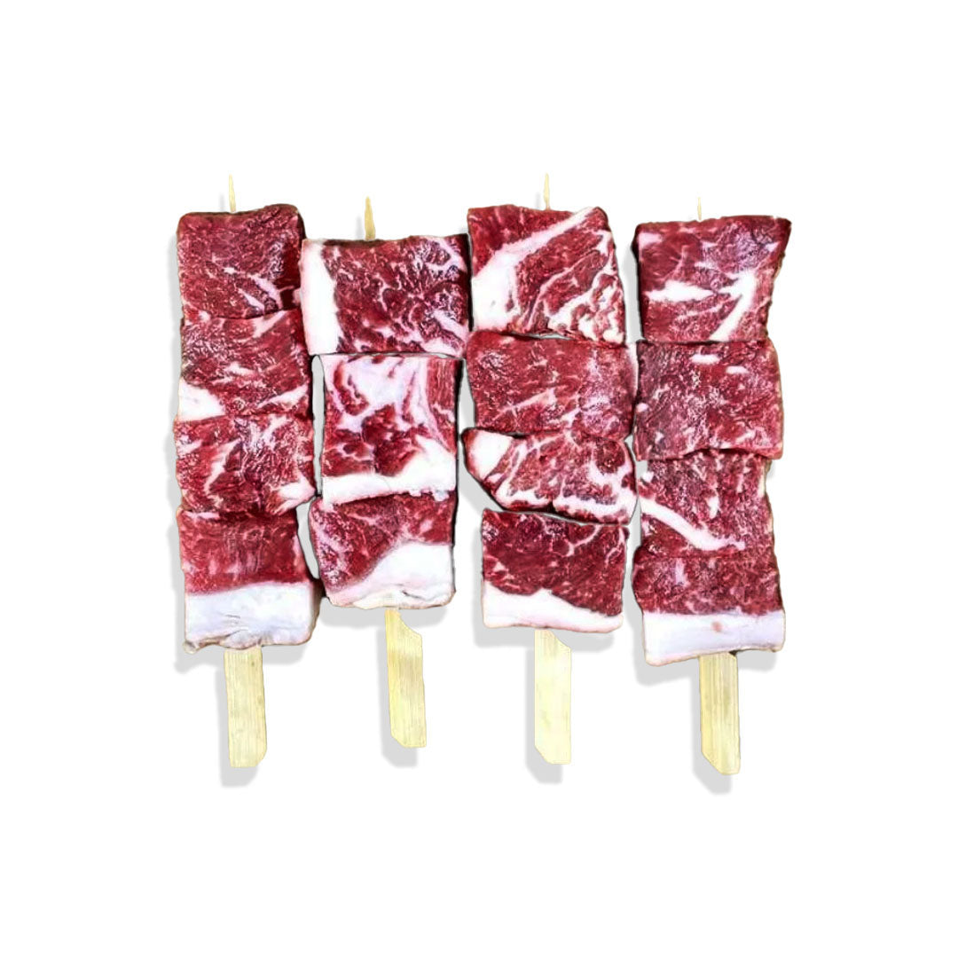 Raw meat skewers on wooden sticks against a white background