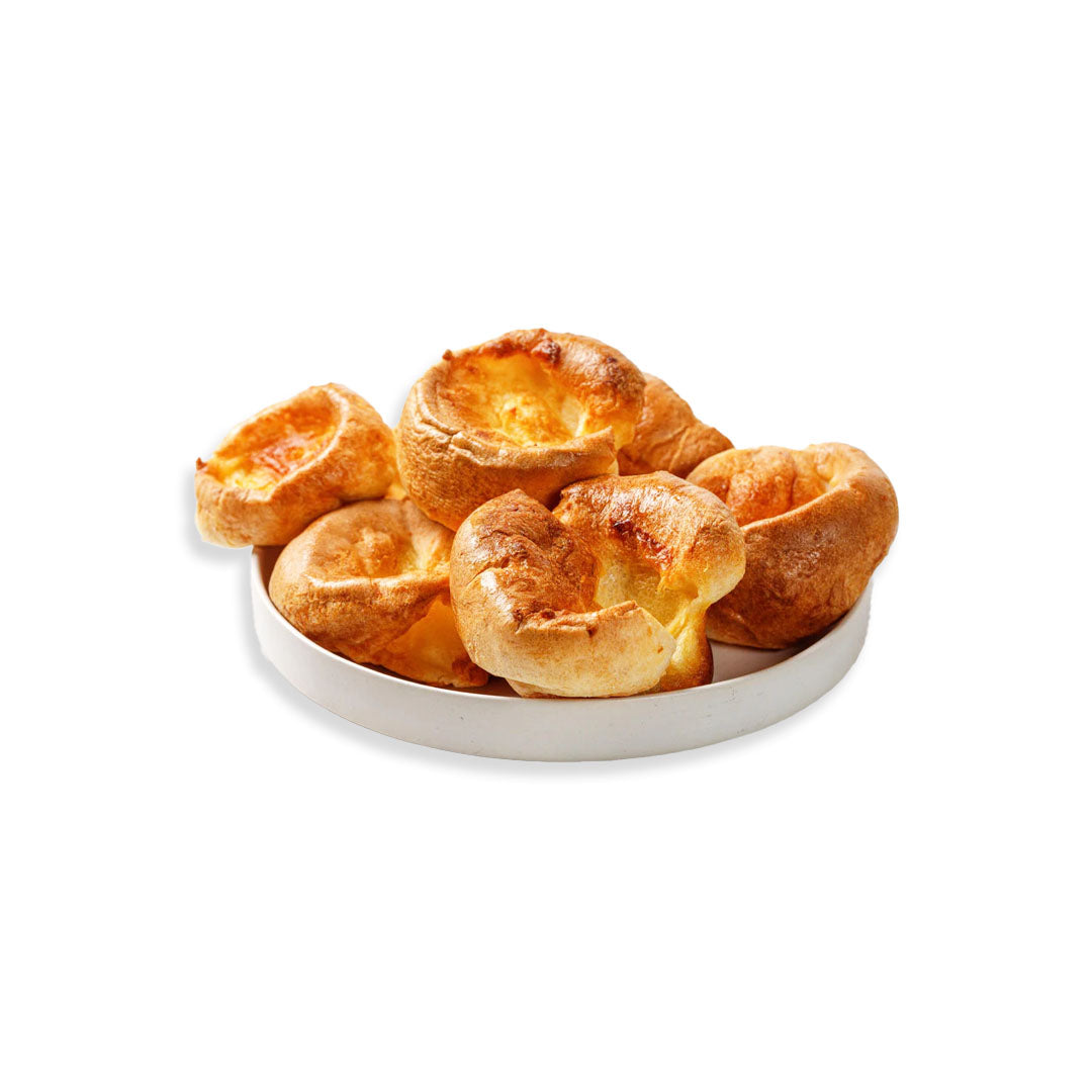 Baked Yorkshire puddings on a white plate with a white background