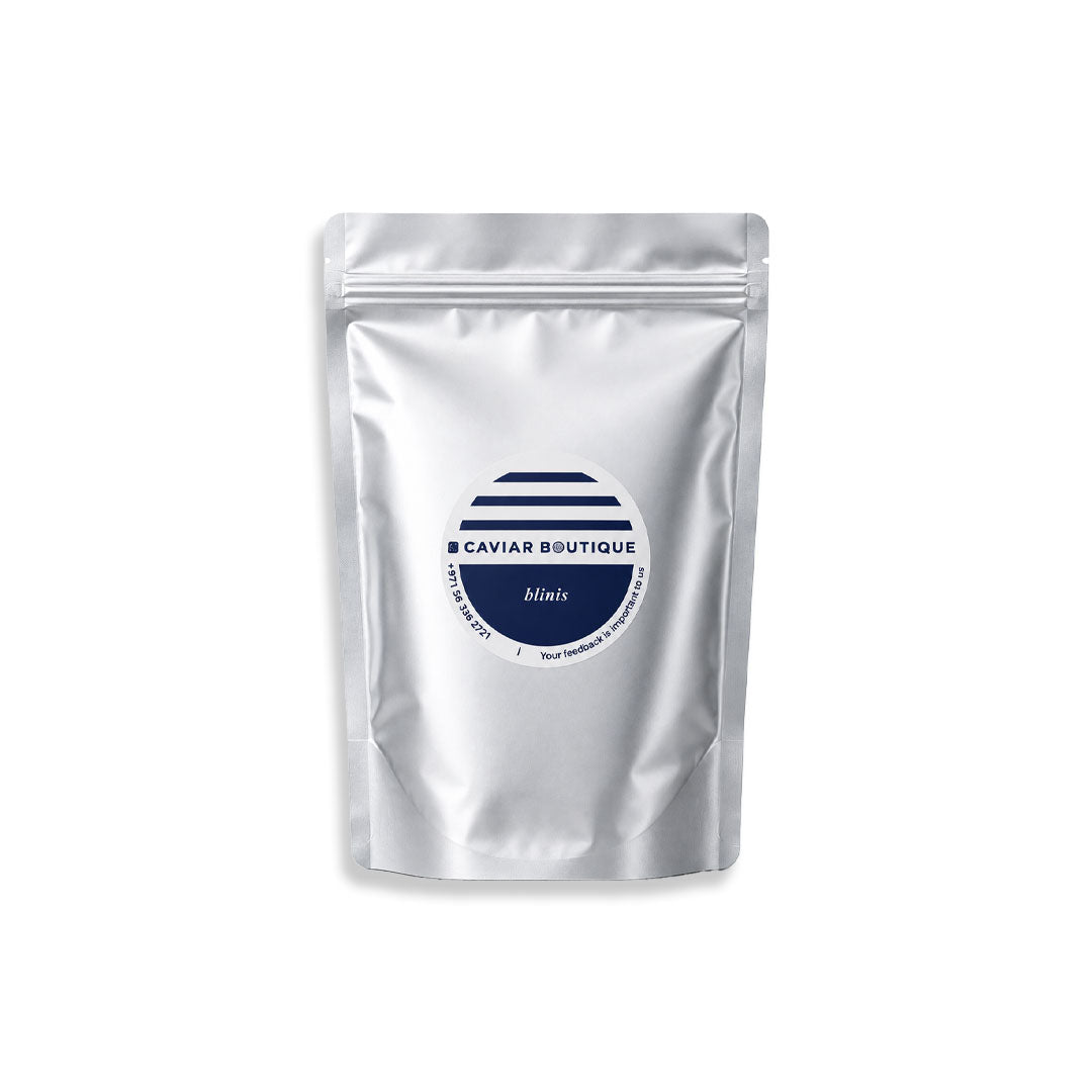 A silver stand-up pouch package with a circular navy and white label reading 'CAVIAR BIUTIQUE' and 'blinis', centered on a plain white background.