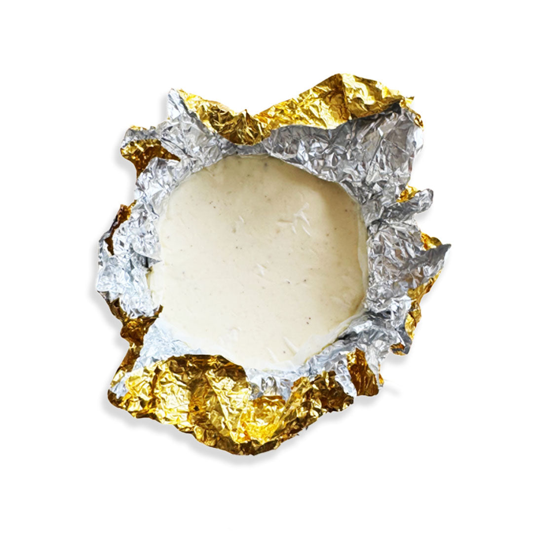 White chocolate truffle wrapped in gold leaf on a white background