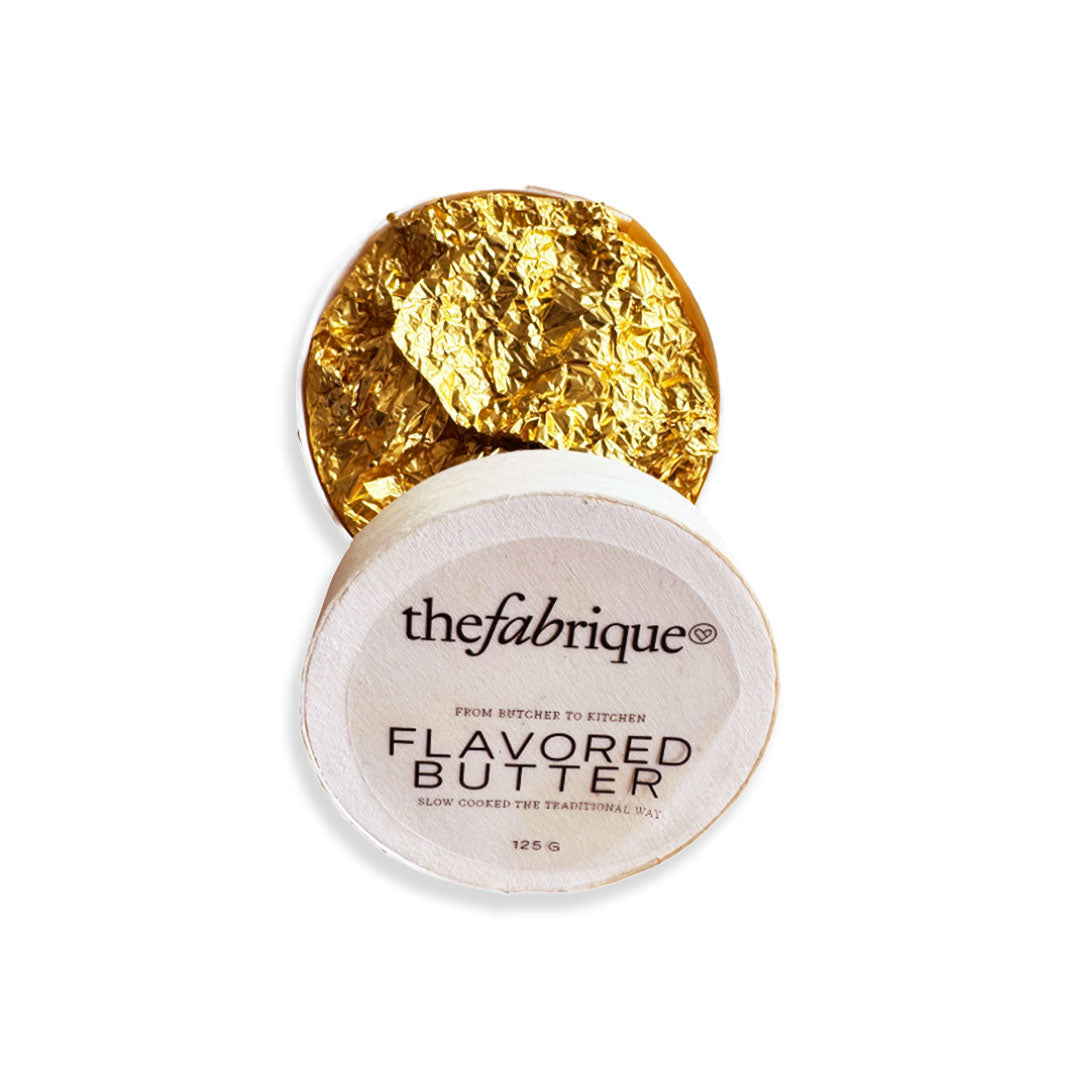 Gold leaf on a container labeled 'thefabrique Flavored Butter' on a white background