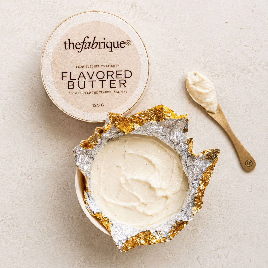Flavored butter container with a spoonful of butter on a neutral background