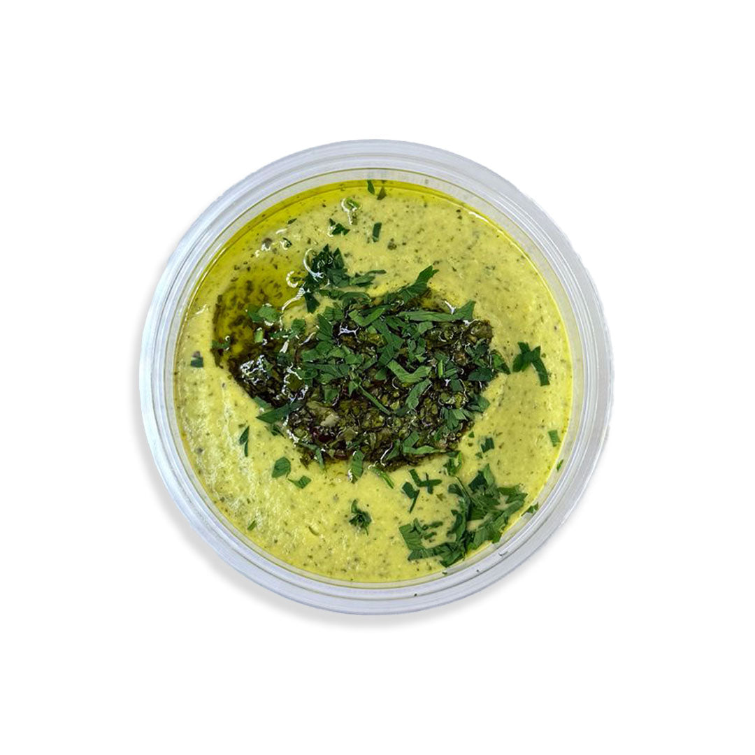 Green herb dip in a round container on a white background