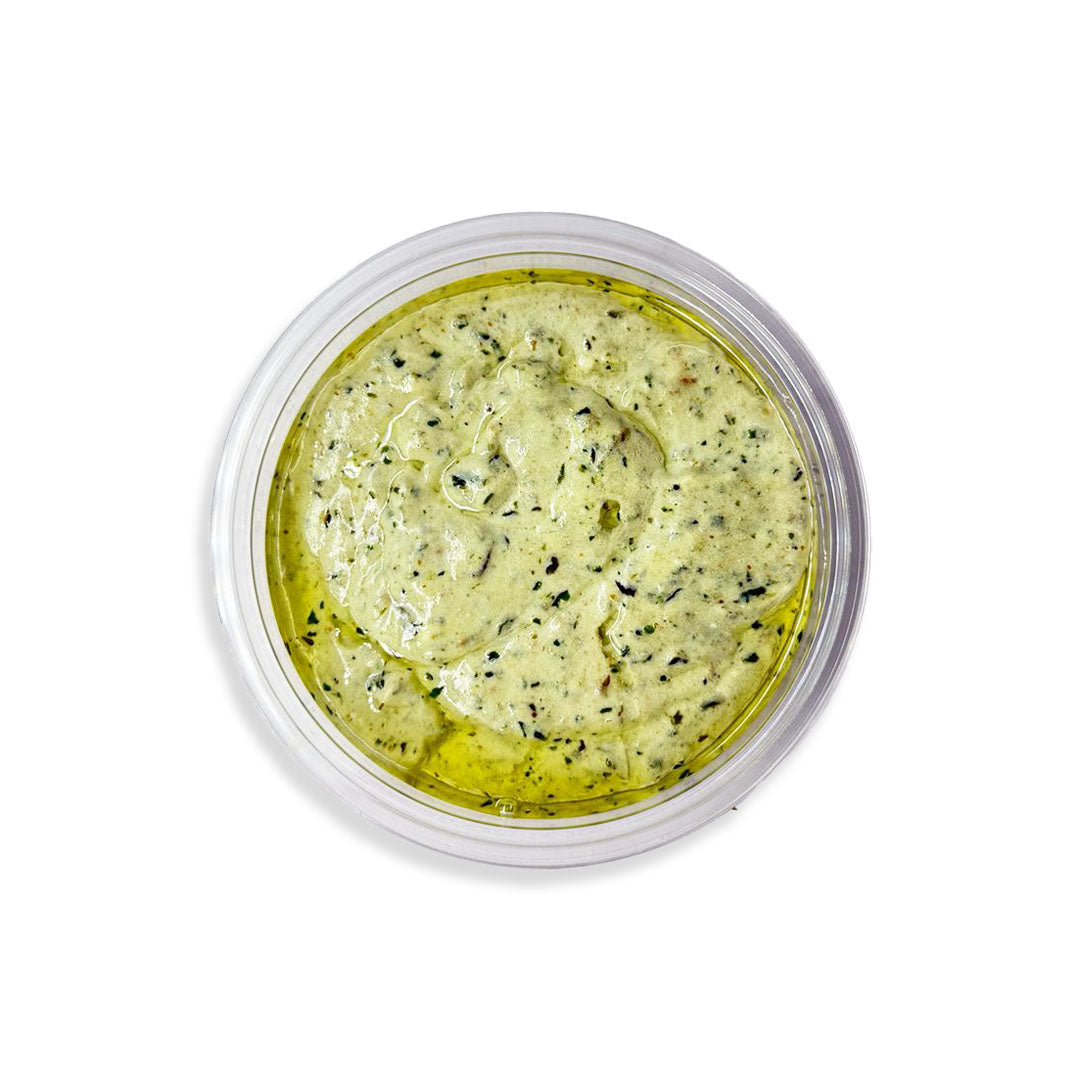 Green herb spread in a clear container on a white background