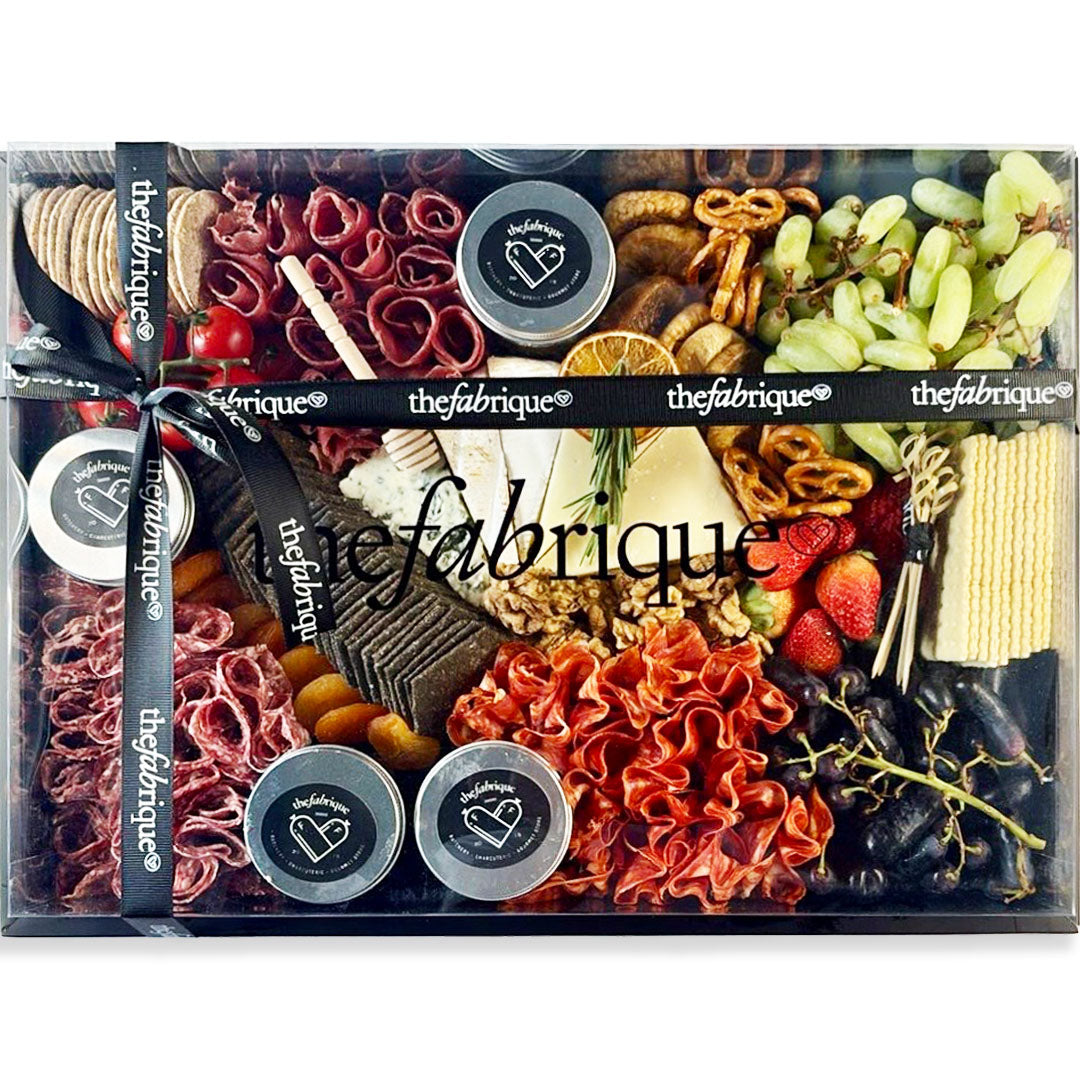 Gourmet food platter with various snacks and cheeses, branded 'thefabrique'.