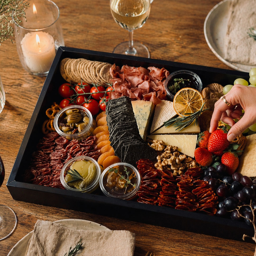 Assorted charcuterie board with meats, cheeses, fruits, and nuts on a wooden table.