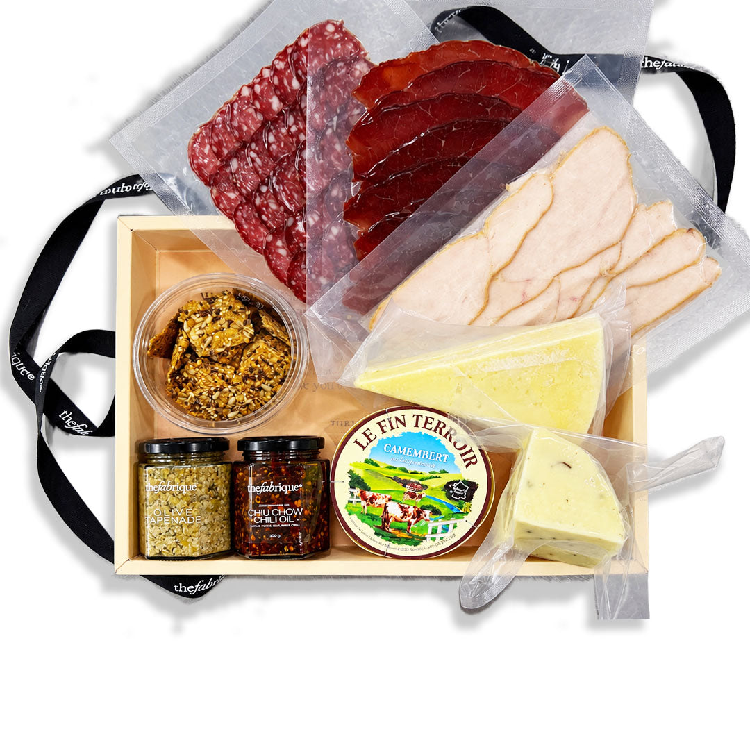A gourmet charcuterie board gift box from Le Fin Terrioul, featuring sliced meats, cheeses, spreads, and condiments in a wooden tray with a black ribbon.