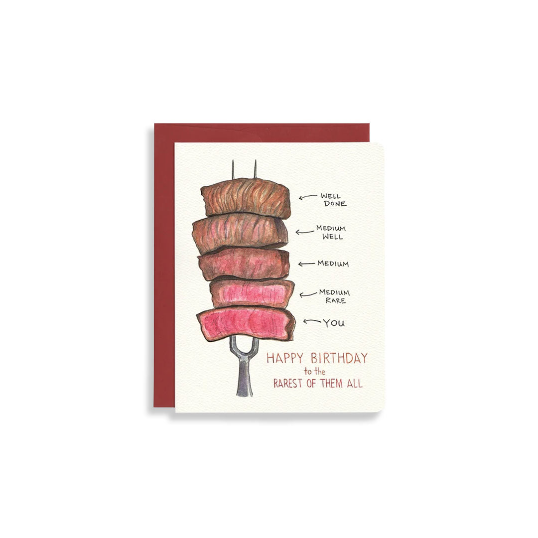 A birthday greeting card featuring an illustration of a grilled steak skewer with labeled doneness levels and the text 'HAPPY BIRTHDAY to the RAREST OF THEM ALL,' shown with a dark red envelope against a white background.